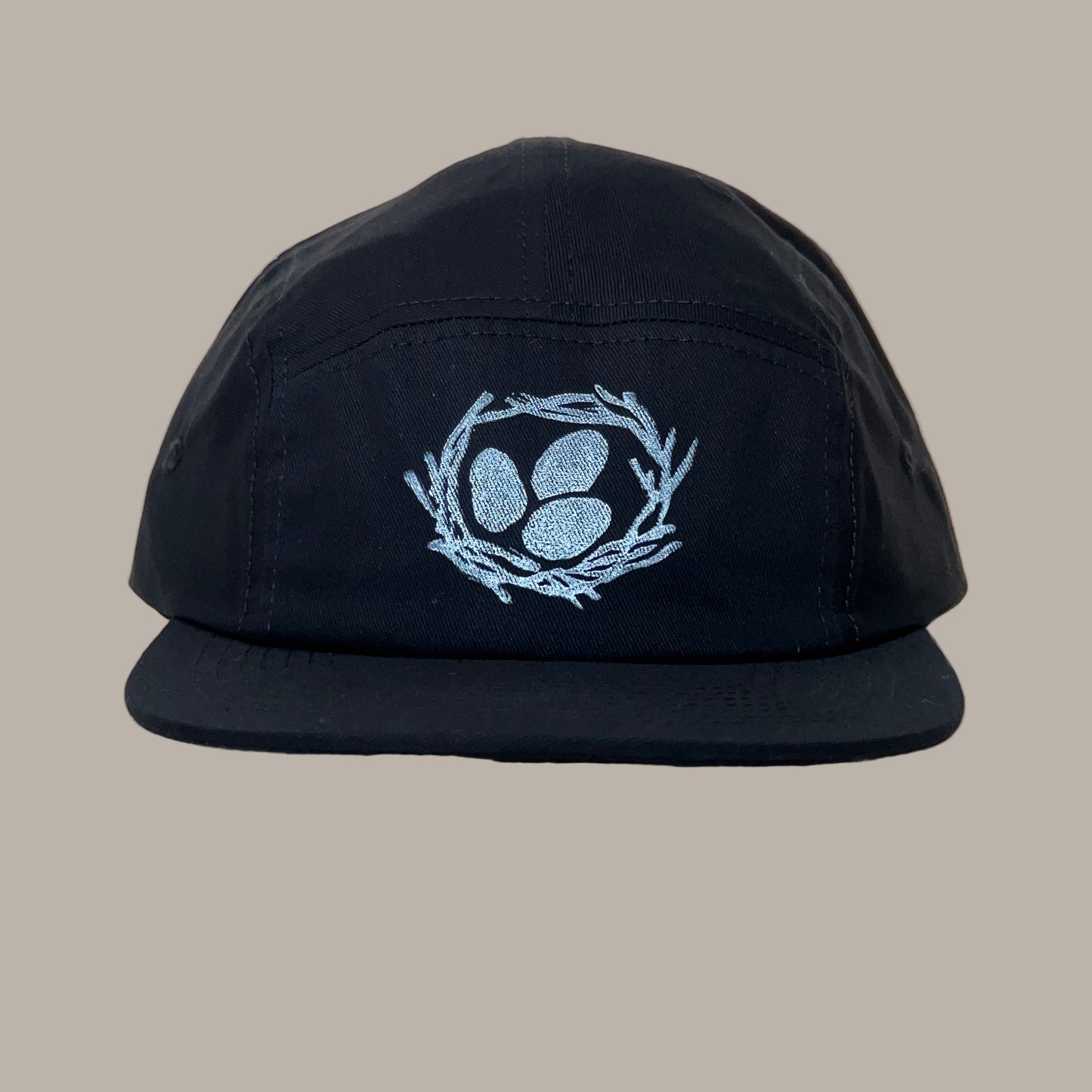 Black cap with a white egg print design on a beige background