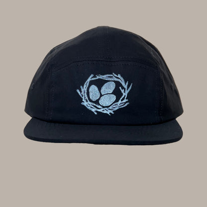 Black cap with a white egg print design on a beige background